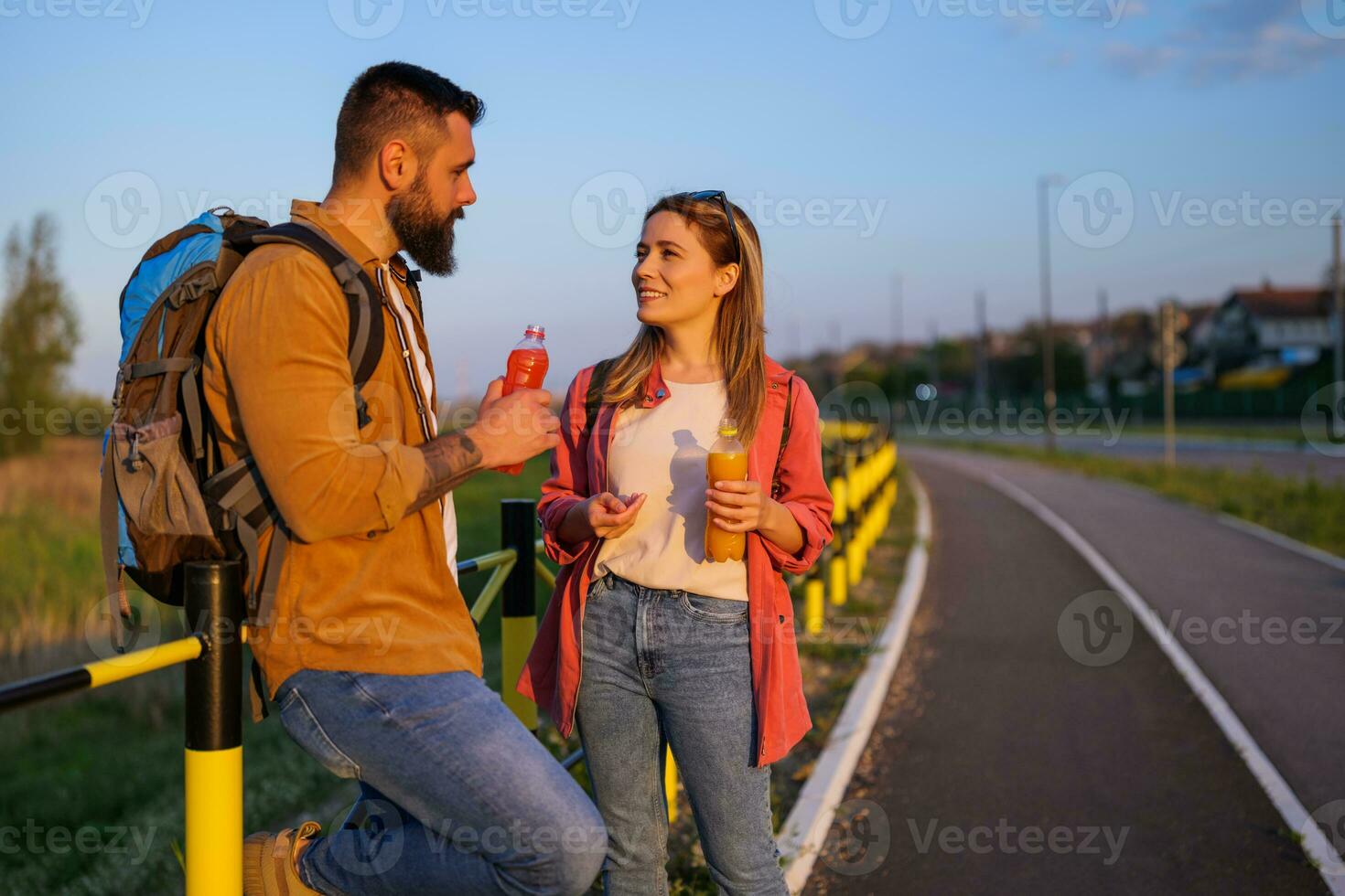adulto casal em repouso ao lado a estrada e bebendo refresco suco. foto