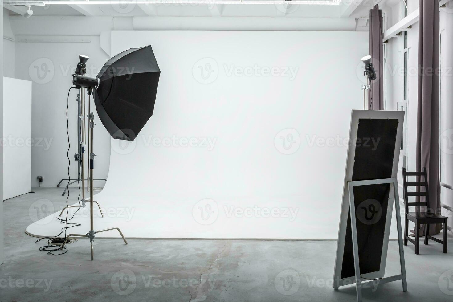interior do espaço brilhante do estúdio fotográfico com grande ciclorama branco com equipamento de iluminação foto
