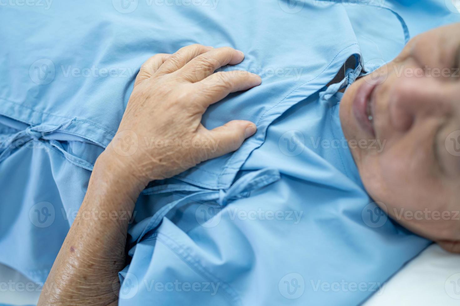 O paciente asiático sênior ou idosa idosa sente dor no peito e no coração na cama, na enfermaria de hospital de enfermagem, conceito médico forte e saudável. foto
