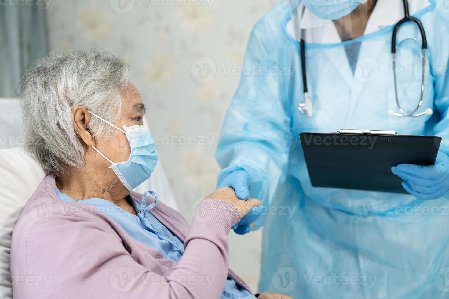 médico asiático usando protetor facial e terno novo normal para verificar o paciente protege a segurança infecção covid-19 surto de coronavírus na enfermaria de quarentena do hospital. foto