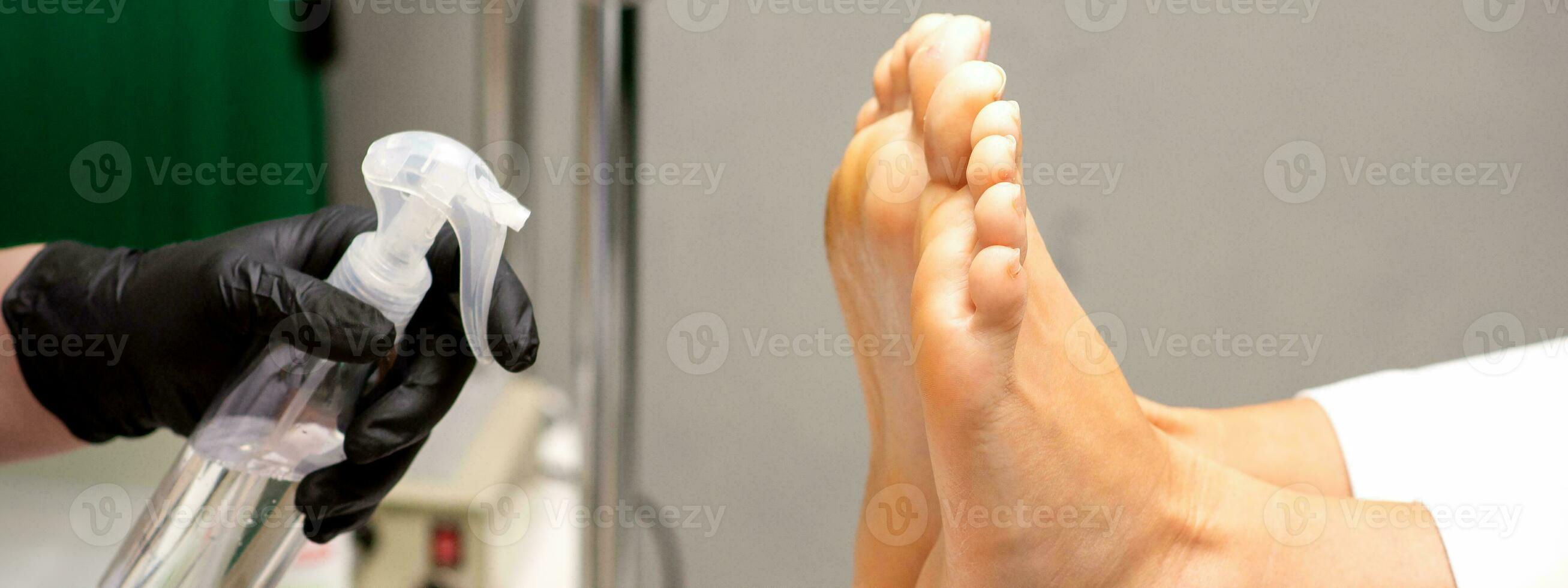 pedicure mestre desinfeta a pés do mulher com a preparação descontaminação dentro beleza salão. foto