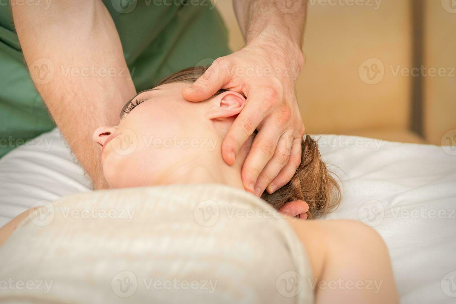 osteopata fazendo massagem em a fêmea cabeça dentro reabilitação clínica Centro. foto