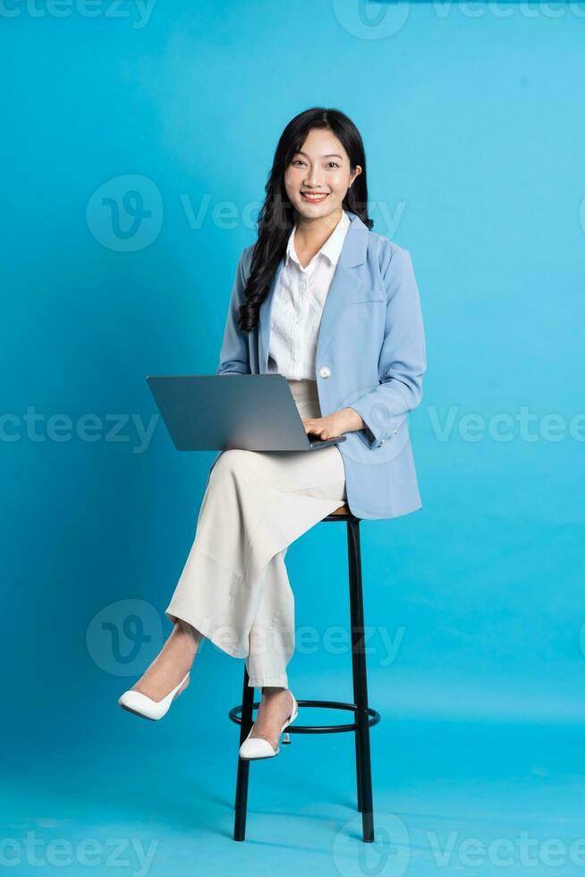 ásia empresária retrato sentado em cadeira, isolado em azul fundo foto