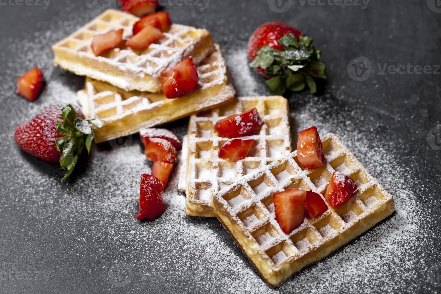 waffers da bélgica com morangos e açúcar em pó no fundo do quadro negro. foto