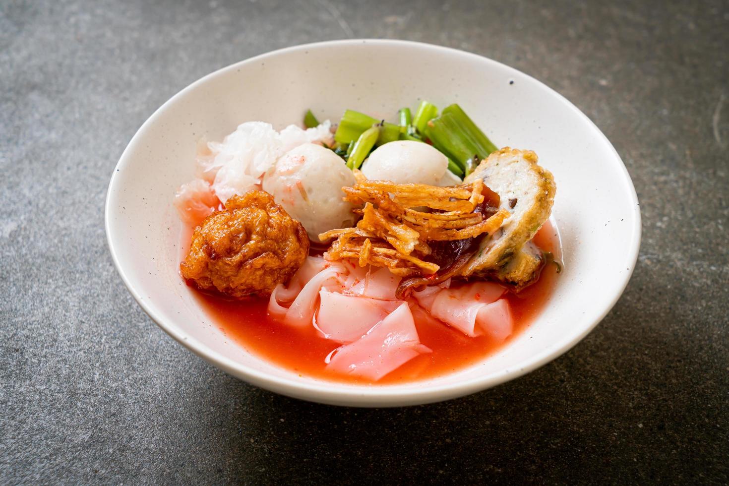 Macarrão estilo tailandês com tofu sortido e bolinho de peixe na sopa vermelha foto