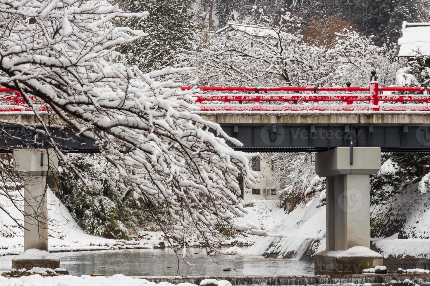 ponte nakabashi com queda de neve e rio miyakawa na temporada de inverno. marco de hida, gifu, takayama, japão. vista da paisagem foto