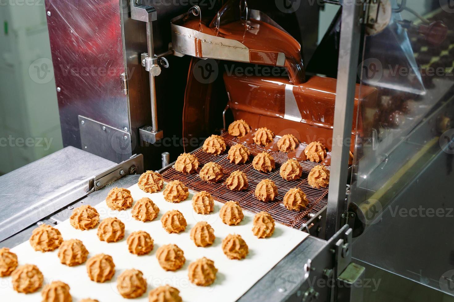 conceito de produção e indústria de doces - processamento de bombons de chocolate na esteira de confeitaria. foto