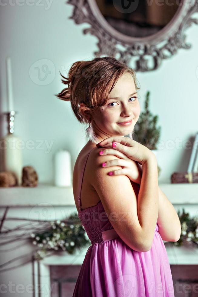 uma jovem com um vestido rosa no fundo de decorações de Natal e uma lareira na sala foto