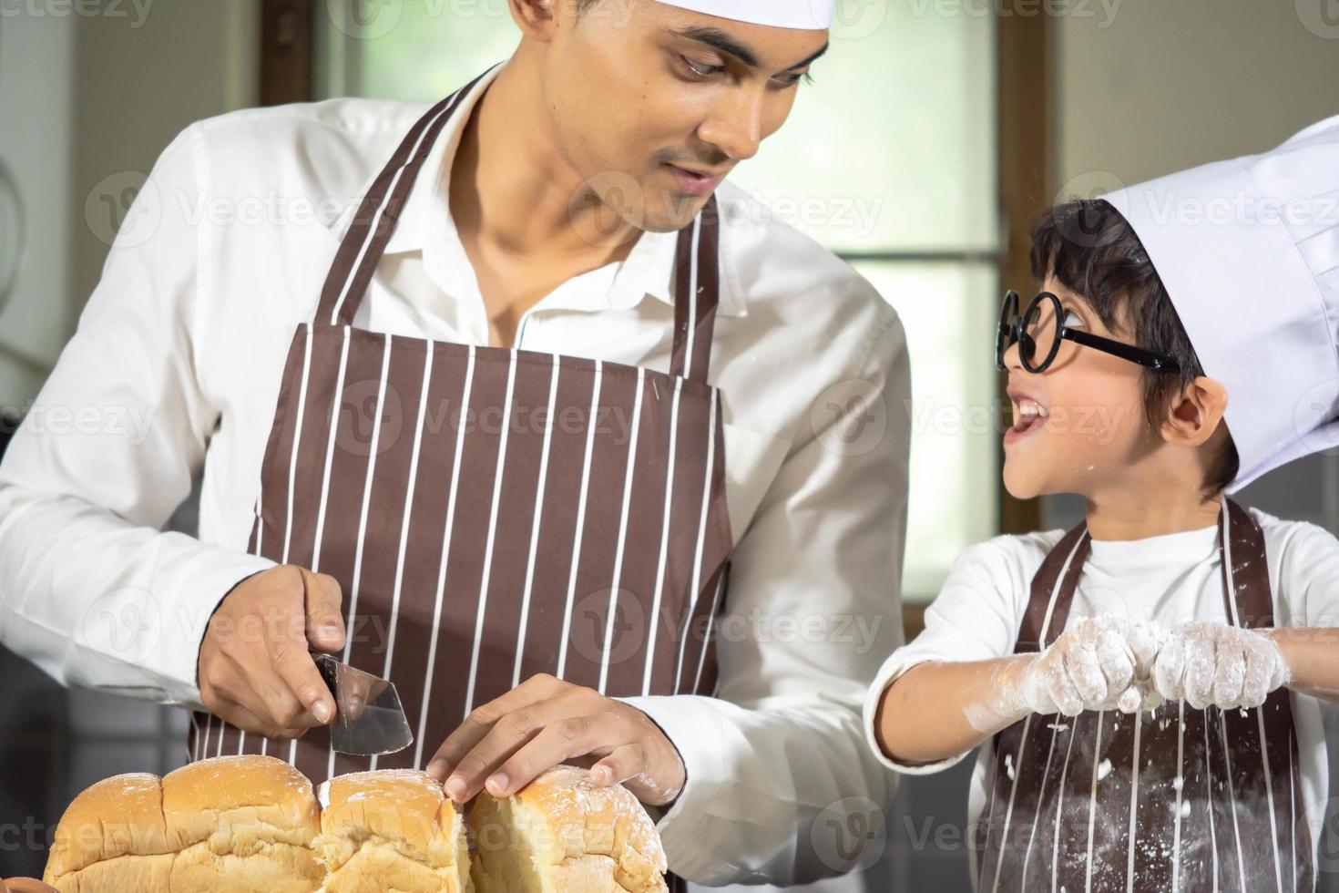 menino asiático usa óculos, provoca o pai cozinhando com farinha branca amassando a massa de pão ensina as crianças a praticar assar ingredientes, pão e ovo em utensílios de mesa na cozinha estilo de vida feliz aprendendo vida com a família foto