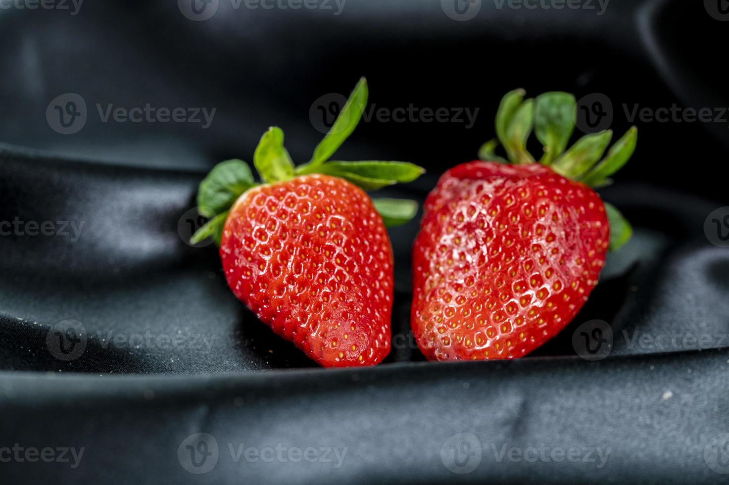 morangos maduros em fundo de tecido de cetim preto foto