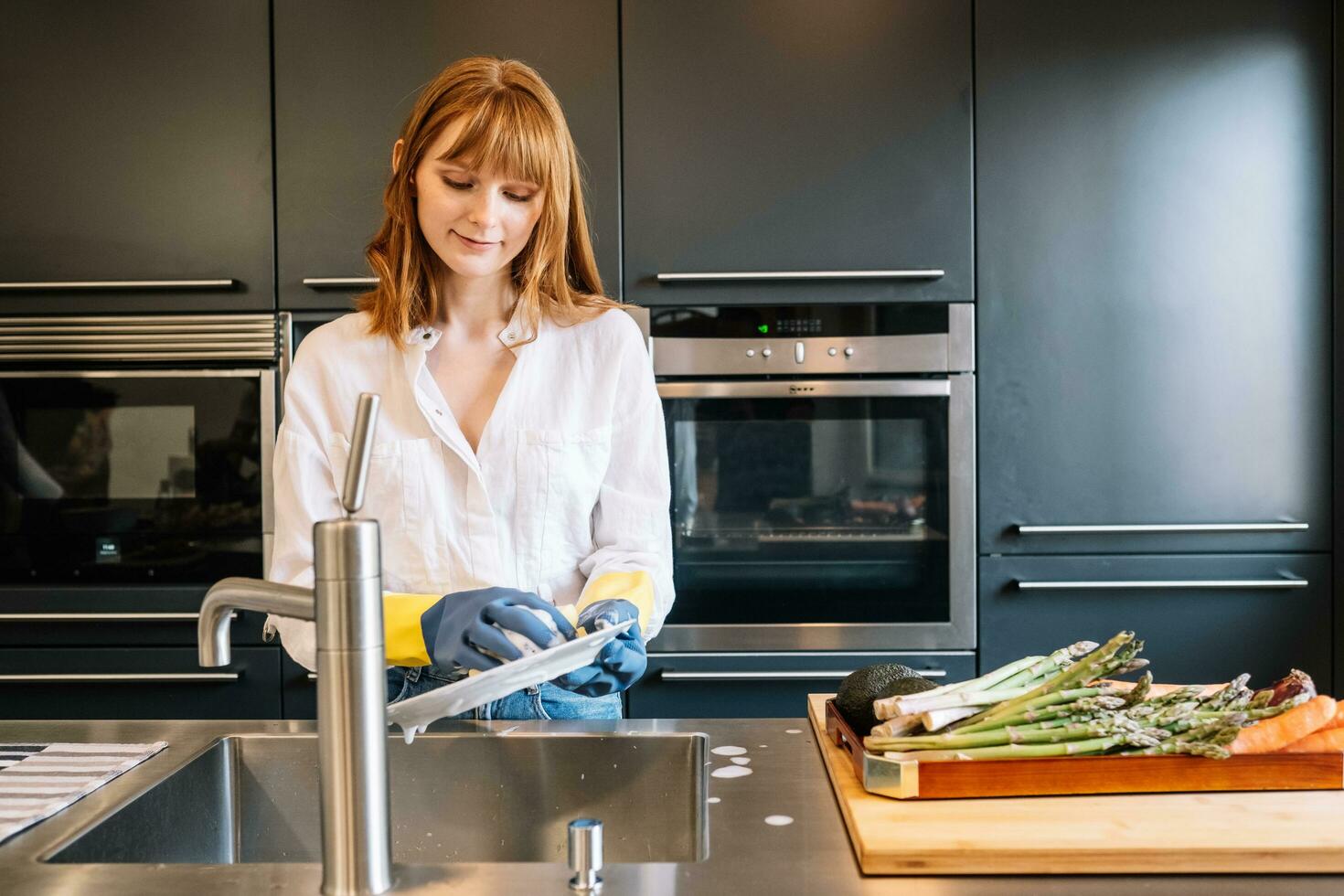 branco mulher com luvas limpo pratos dentro cozinha foto