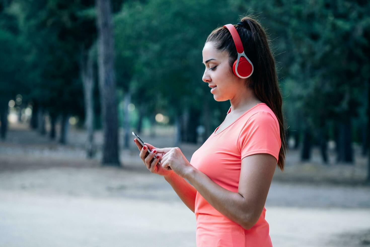 caucasiano mulher ouvindo para música enquanto exercício dentro uma parque foto