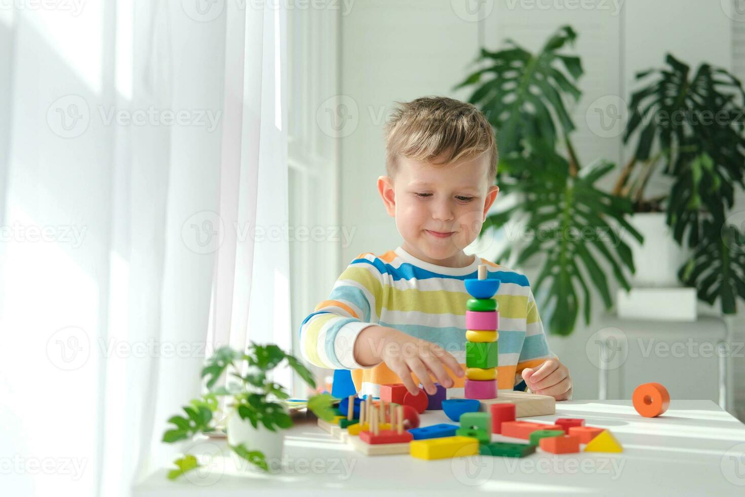 uma pequeno Garoto tocam com de madeira brinquedos e constrói uma torre. educacional lógica brinquedos para crianças. montessori jogos para criança desenvolvimento. crianças de madeira brinquedo. foto