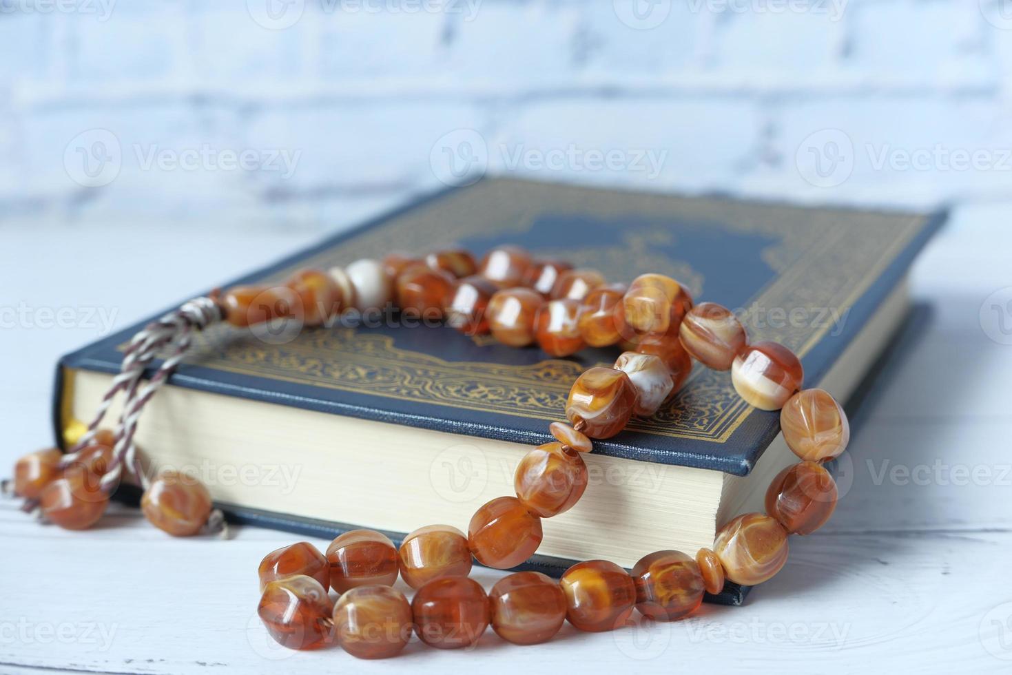 livro sagrado Alcorão e Rosário na mesa, close-up. foto