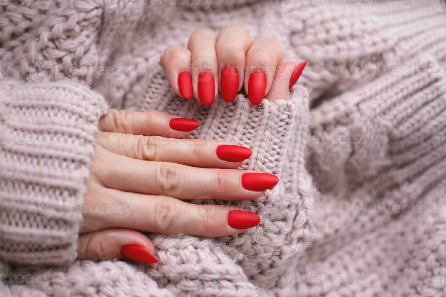 mulheres mãos com uma lindo fosco oval manicure dentro uma caloroso Rosa tricotado suéter. inverno tendência, cobrir vermelho unhas com gel polonês, shellac. foto