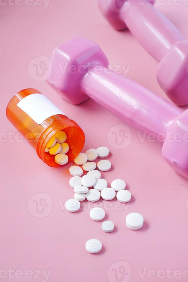 halteres de cor rosa e comprimidos médicos em rosa foto