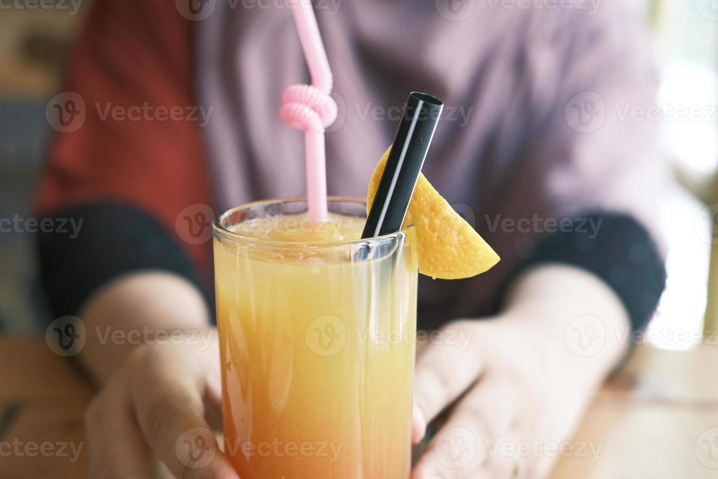 mão de uma mulher segurando um copo de suco de laranja foto