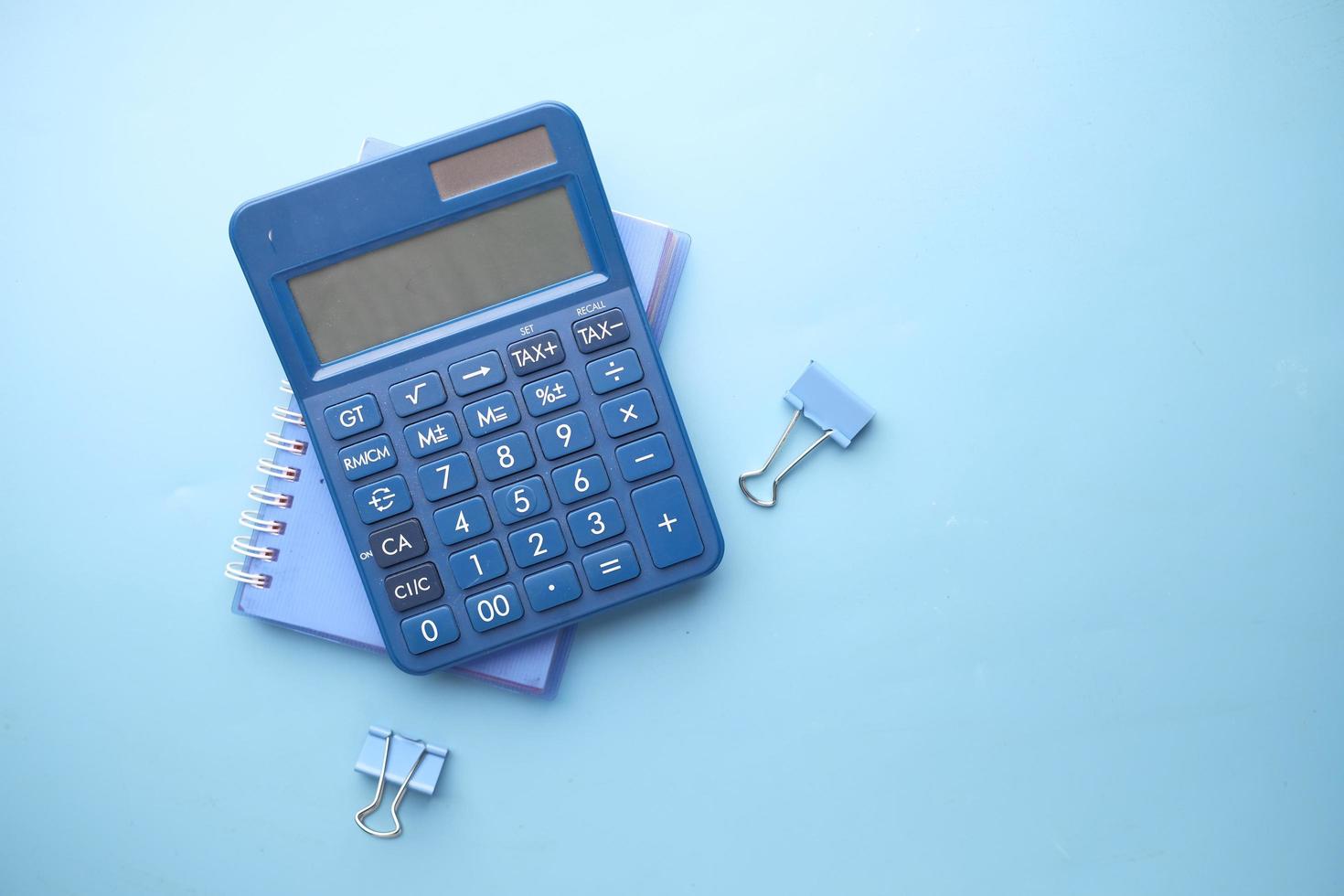 close-up da calculadora azul e do bloco de notas na cor de fundo foto