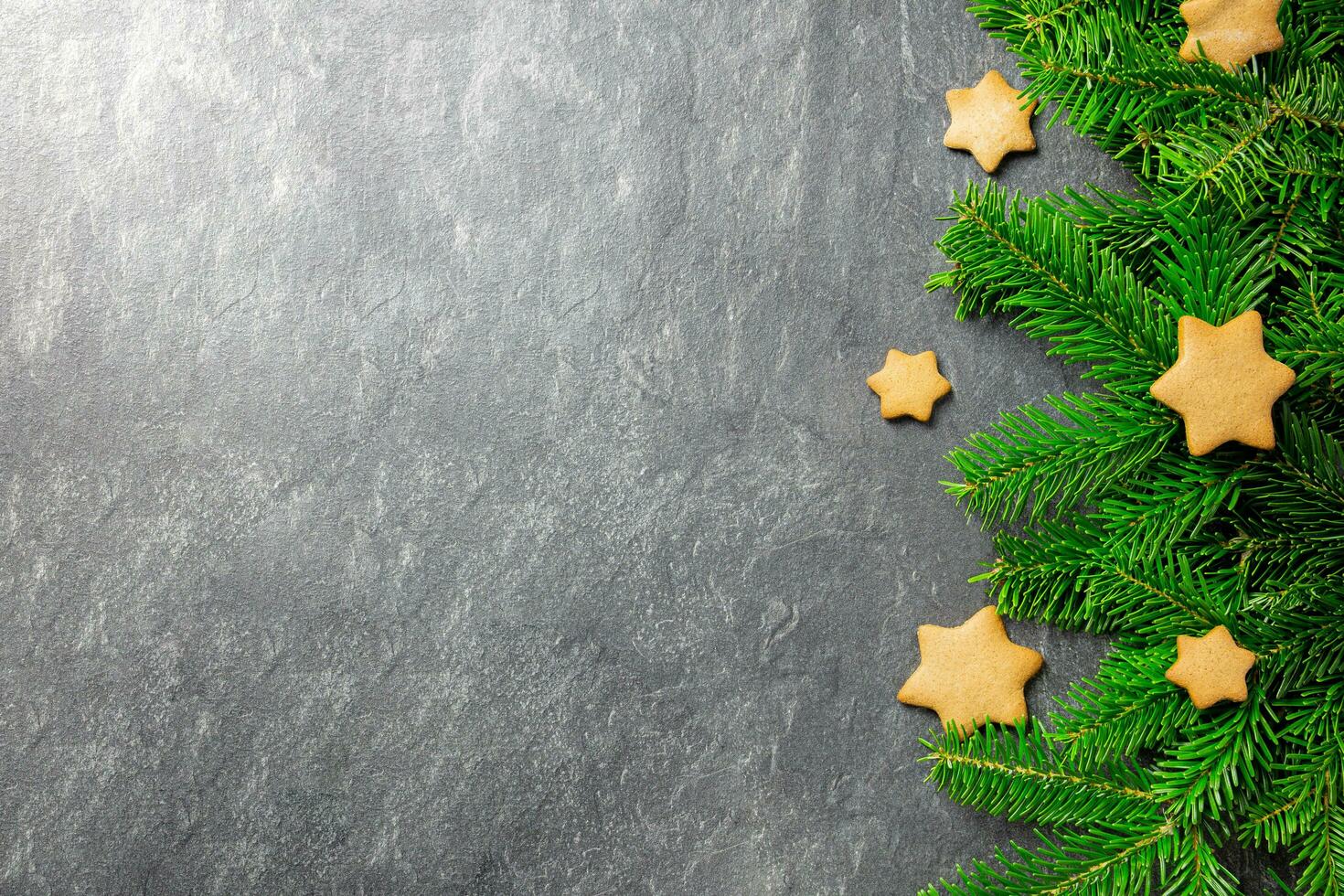 Natal tradicional Pão de gengibre estrelas biscoitos com Natal árvore galhos em uma Sombrio pedra fundo. topo visualizar. cópia de espaço. foto