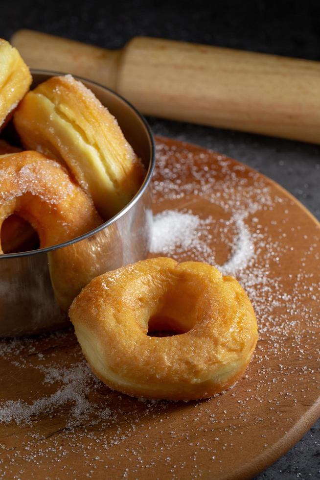 donuts com açúcar em uma placa de madeira sobre um fundo escuro de mesa foto