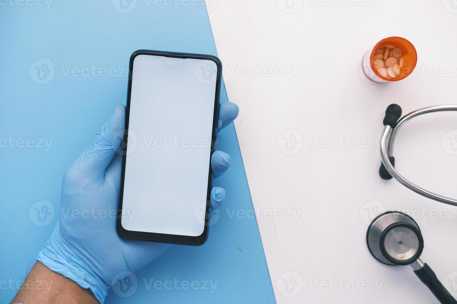 mão em luvas de látex segurando telefone inteligente com tela verde foto