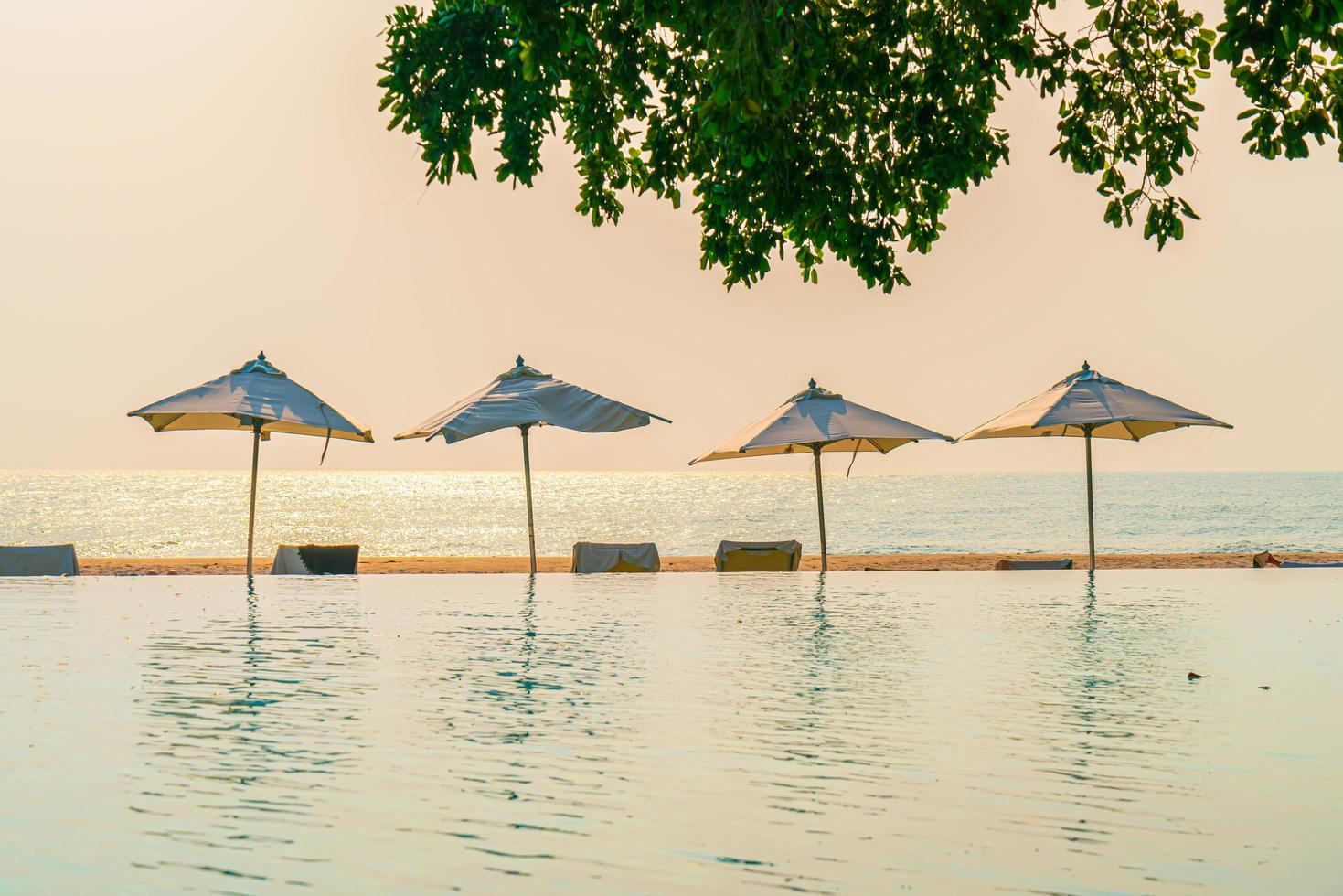 guarda-sol e cadeira ao redor da piscina com vista para o mar foto