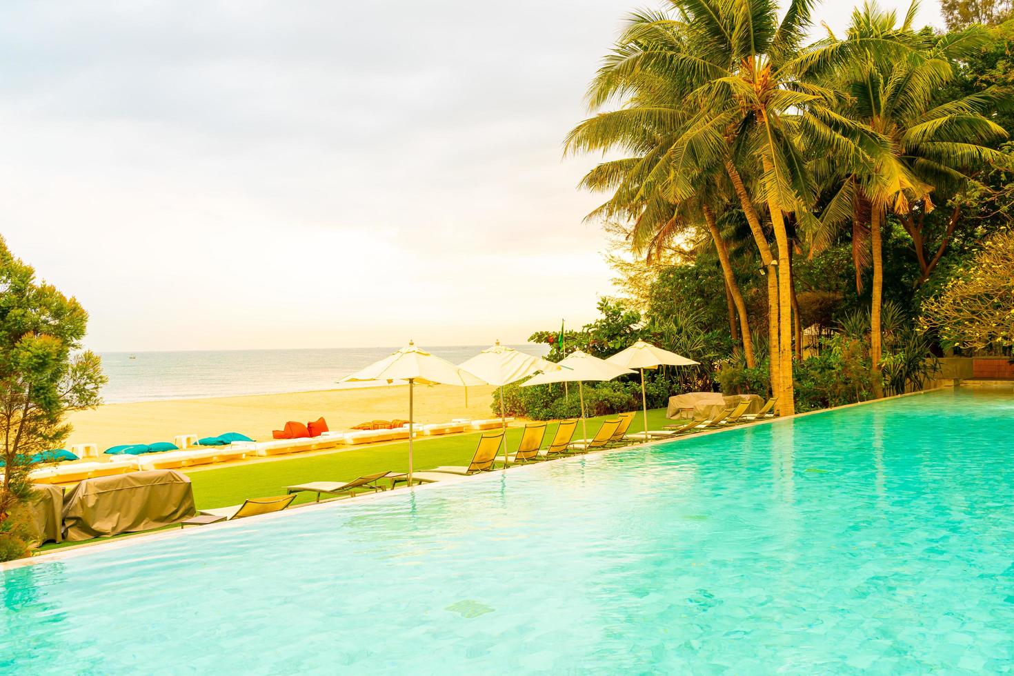 guarda-sol e cadeira ao redor da piscina com vista para o mar foto