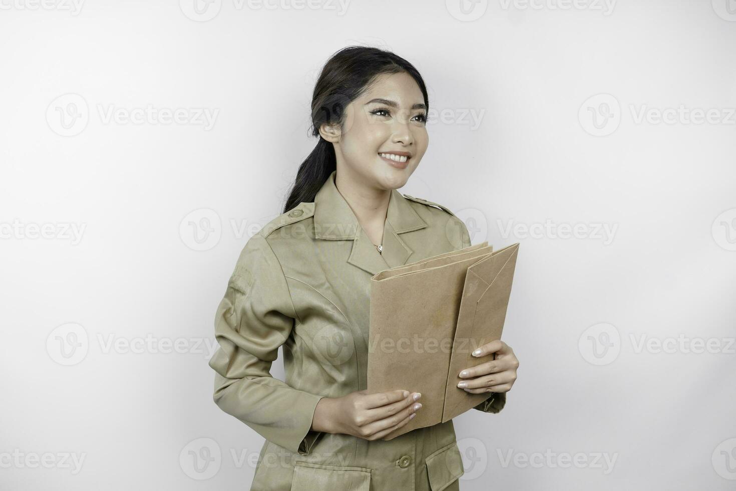 um jovem e belo trabalhador asiático com uniforme marrom trazendo documento. pns indonésio. foto