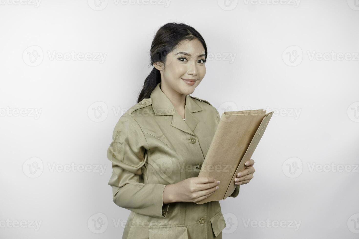 um jovem e belo trabalhador asiático com uniforme marrom trazendo documento. pns indonésio. foto