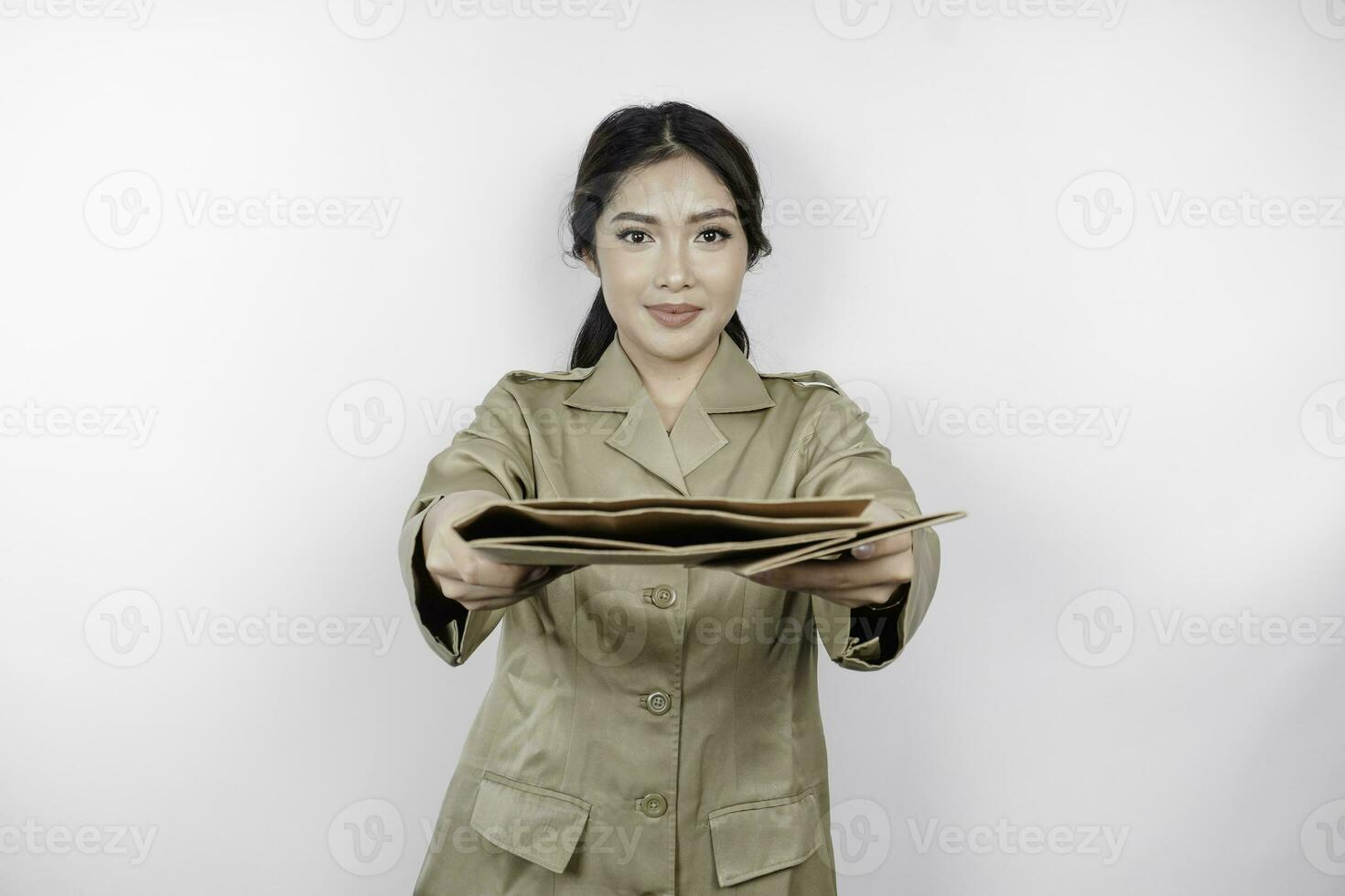 uma jovem lindo ásia trabalhador com Castanho uniforme trazendo documento e entrega isto para a Câmera. indonésio pns. foto