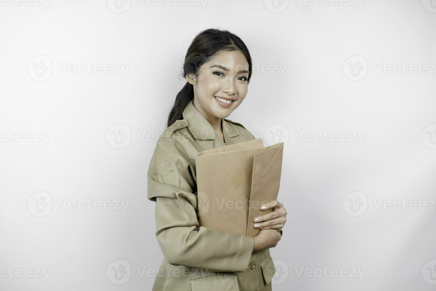 um jovem e belo trabalhador asiático com uniforme marrom trazendo documento. pns indonésio. foto