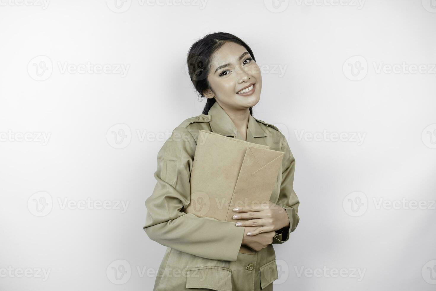 um jovem e belo trabalhador asiático com uniforme marrom trazendo documento. pns indonésio. foto