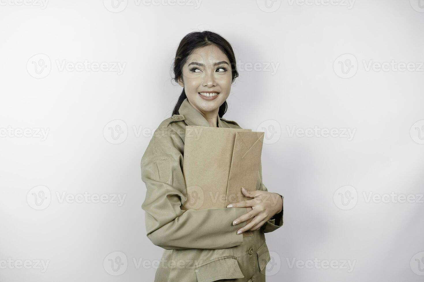 um jovem e belo trabalhador asiático com uniforme marrom trazendo documento. pns indonésio. foto