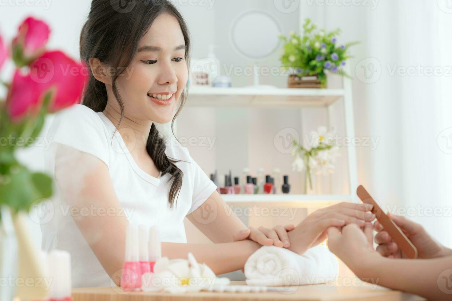 mulher recebe serviço de atendimento por manicure esteticista profissional no centro de spa. salão de beleza de unhas usa lixa de unha para tratamento de esmalte. manicure faz cliente de unha bonita. tratamento de spa para cuidados com o corpo foto