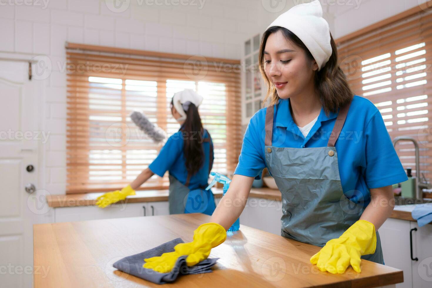 retrato do jovem ásia mulher limpeza a mesa dentro a cozinha às casa foto