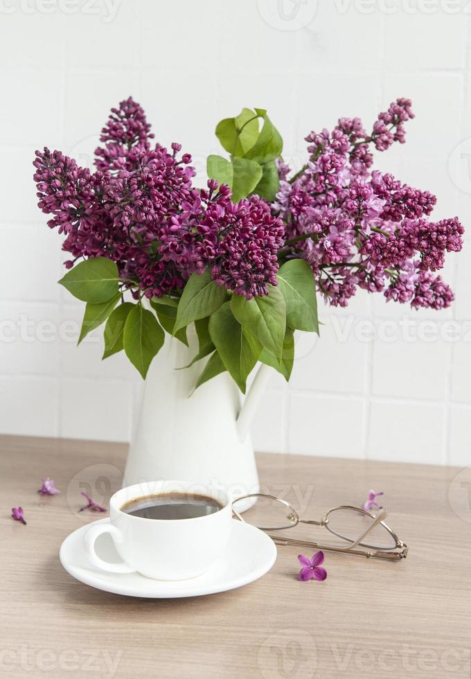 buquê de flores lilás em um vaso e uma xícara de café foto