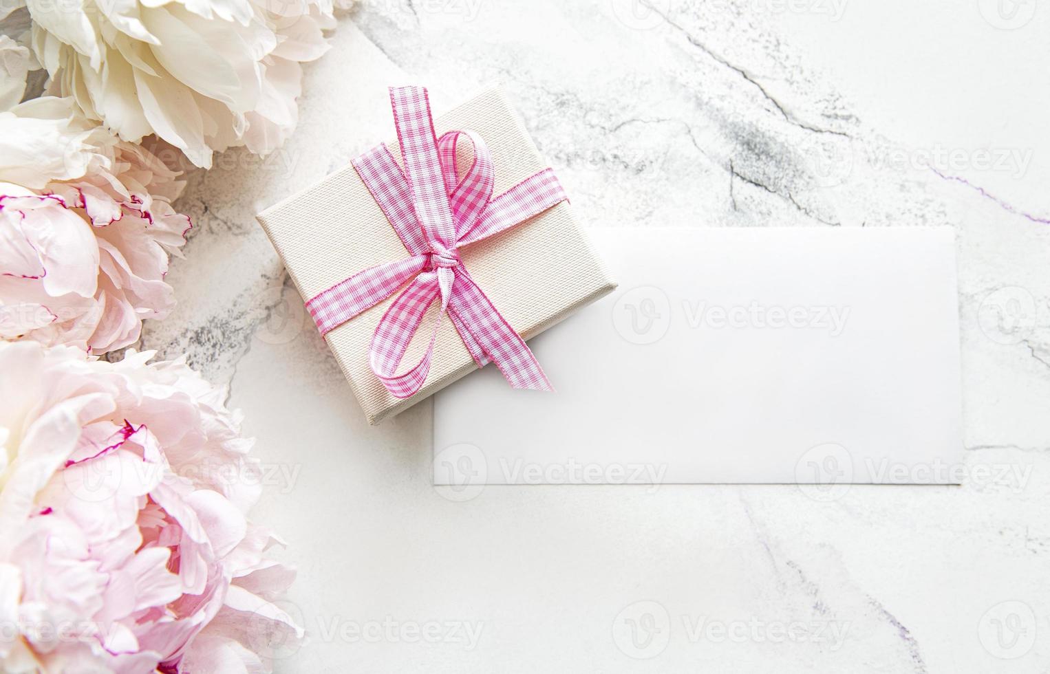 peônias rosa com cartão vazio e caixa de presente em fundo de mármore branco foto