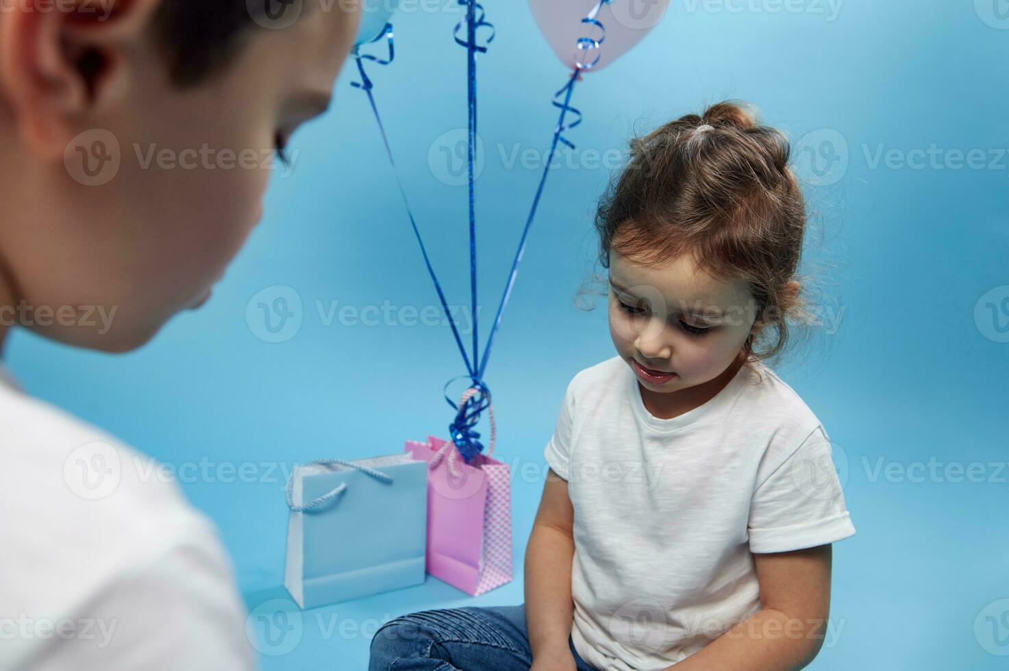 Garoto e menina olhando baixa em azul fundo com cópia de espaço foto