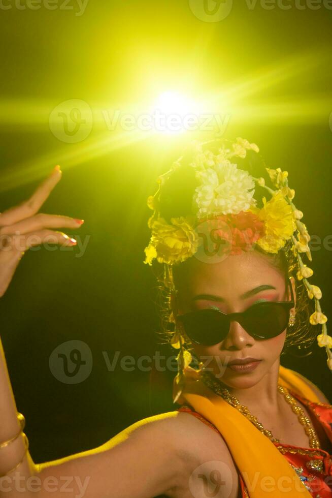 uma javanese dançarino danças muito habilmente enquanto vestindo oculos de sol em dela olhos e muito lindo facial Maquiagem foto