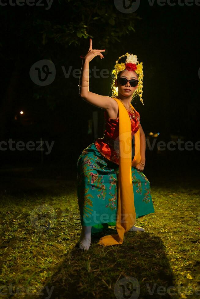 uma javanese dançarino danças muito habilmente enquanto vestindo oculos de sol em dela olhos e muito lindo facial Maquiagem foto