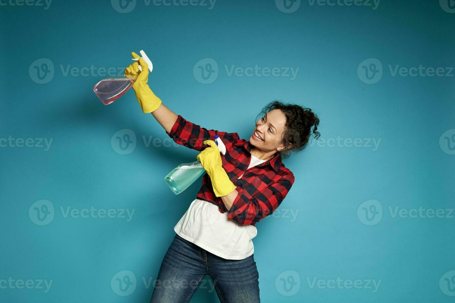 jovem mulher jogando com limpeza sprays Como E se tiroteio uma pistola. posando sobre azul fundo com cópia de espaço. limpeza e casa trabalhos conceito foto
