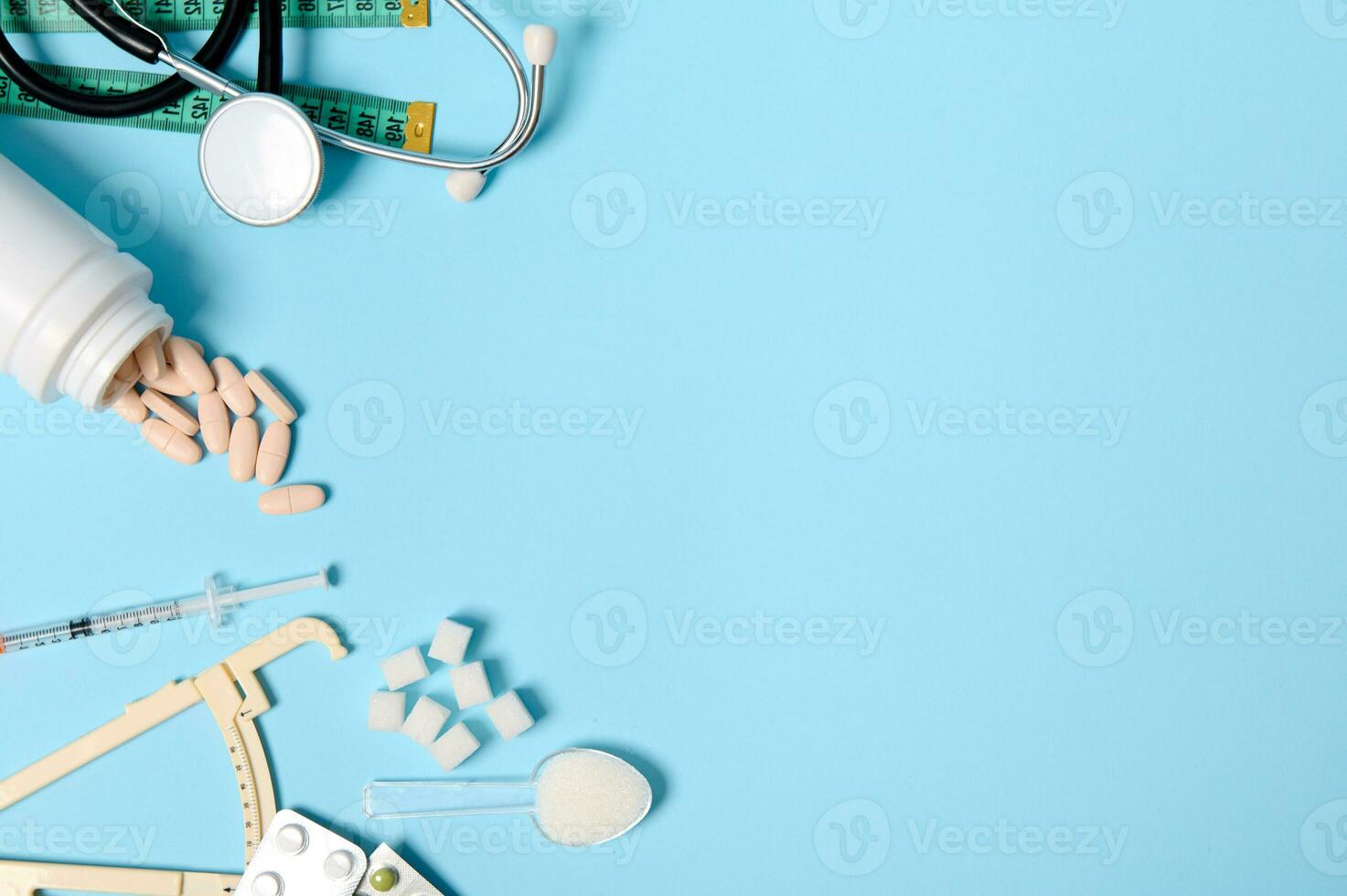 espalhados farmacêutico pílulas, bolhas do comprimidos, insulina seringa, estetoscópio, paquímetro, medindo fita e refinado açúcar em azul fundo, cópia de espaço para diabetes consciência dia, 14 novembro foto