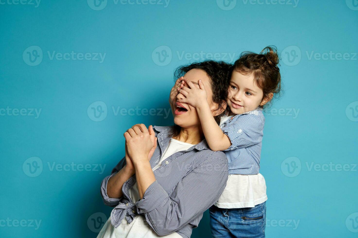 fofa menina abraços dela mãe cobertura dela olhos com dela mãos. emoções. jogar. amor, Cuidado, ternura, feliz infância conceito. foto