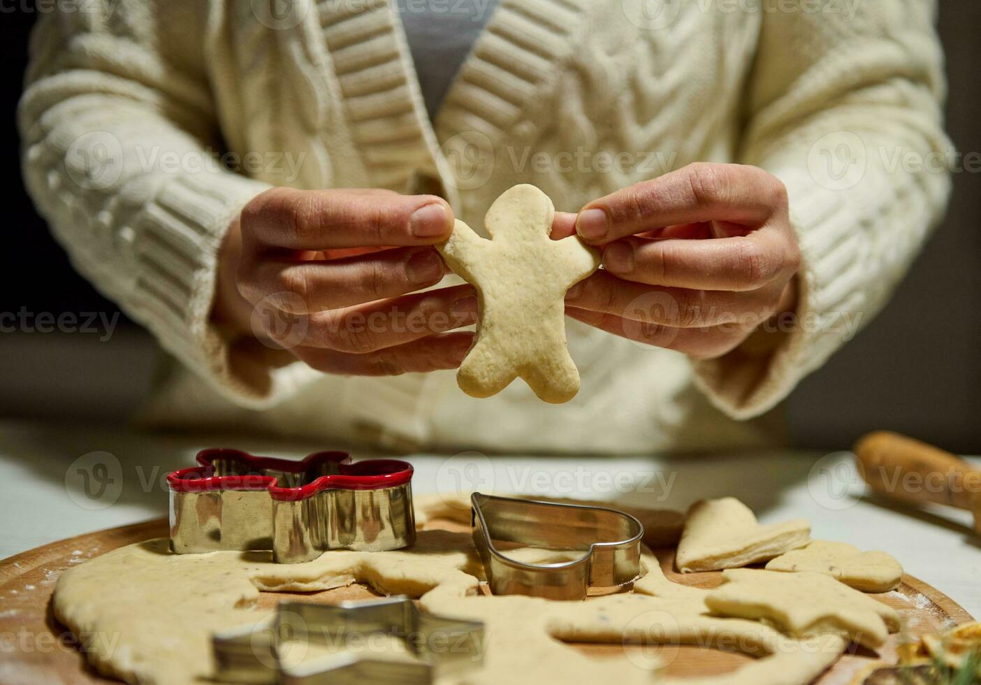 fechar acima do chef mãos segurando uma homem em forma cortar Fora Pão de gengibre massa enquanto fazer Natal biscoitos dentro a cozinha foto