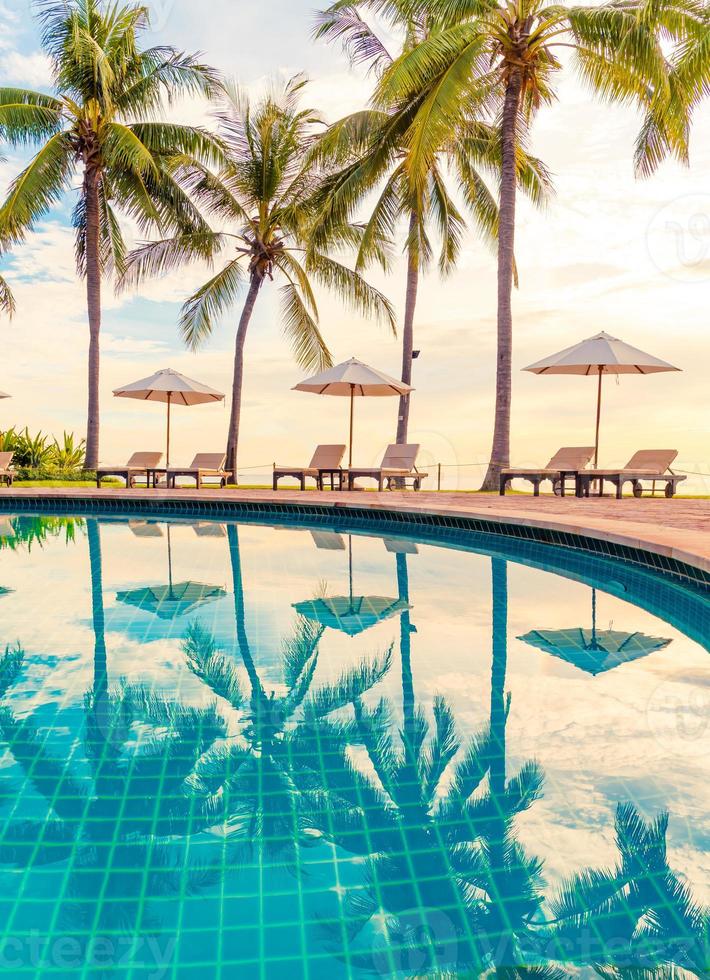 guarda-sol e cadeira ao redor da piscina em hotel resort para viagens de lazer e férias perto da praia do mar foto