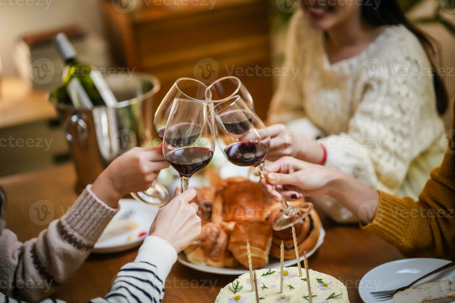 alegre amigos desfrutando casa aniversário feriado Festa. ásia amigos torcendo bebendo vermelho vinho a comemorar Natal ou Novo ano festa foto