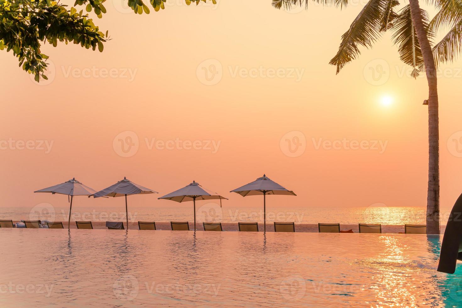 guarda-sol e cadeira ao redor da piscina com vista para o mar foto