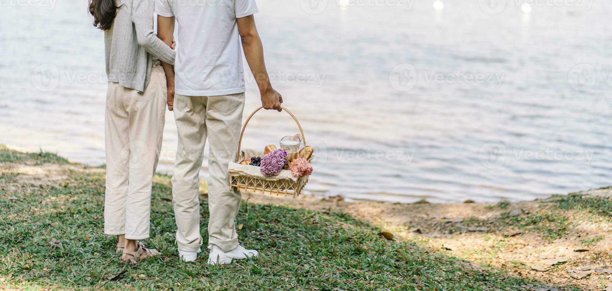 casal caminhando dentro jardim com piquenique cesta. dentro amor casal é desfrutando piquenique Tempo dentro parque ao ar livre foto