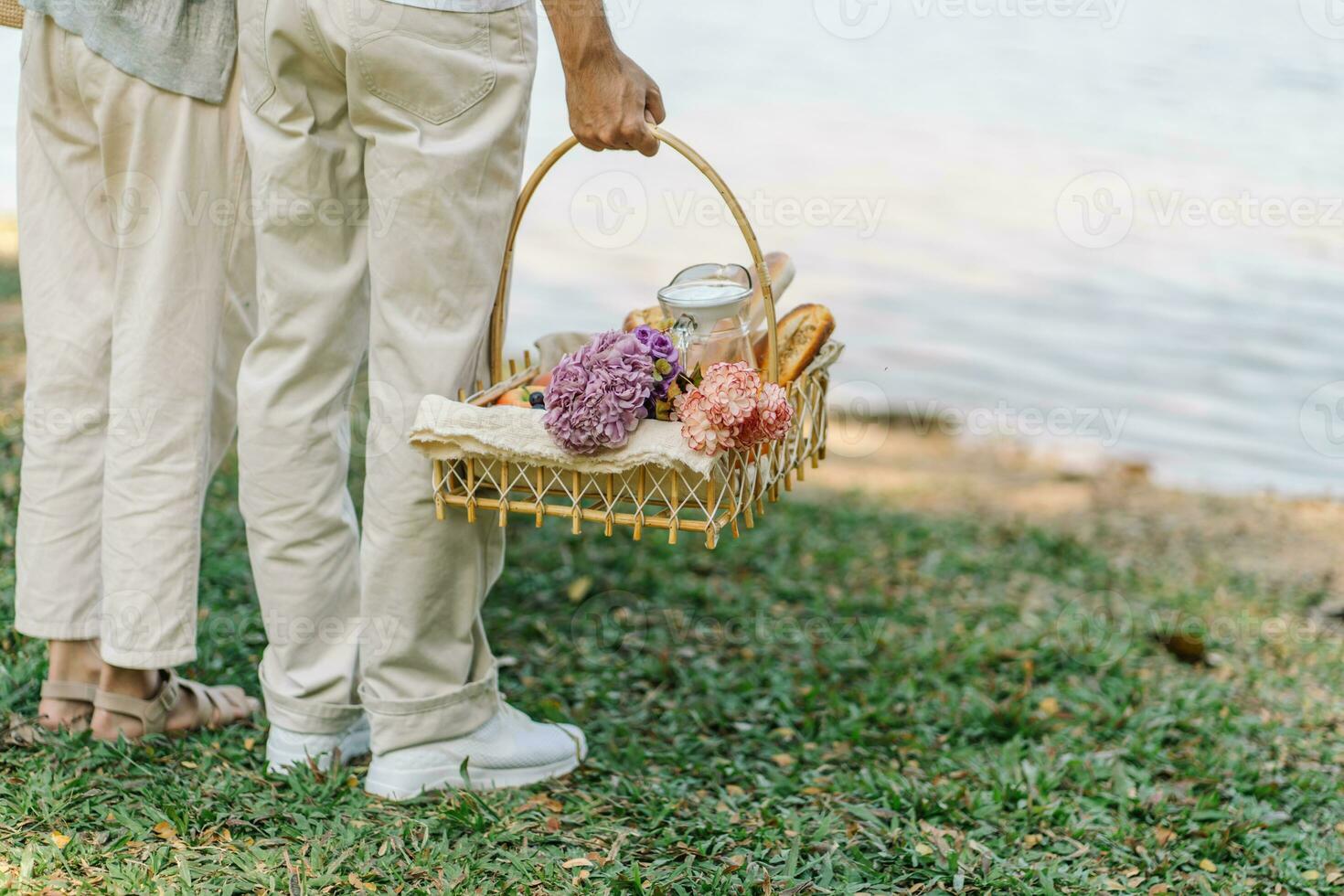 casal caminhando dentro jardim com piquenique cesta. dentro amor casal é desfrutando piquenique Tempo dentro parque ao ar livre foto