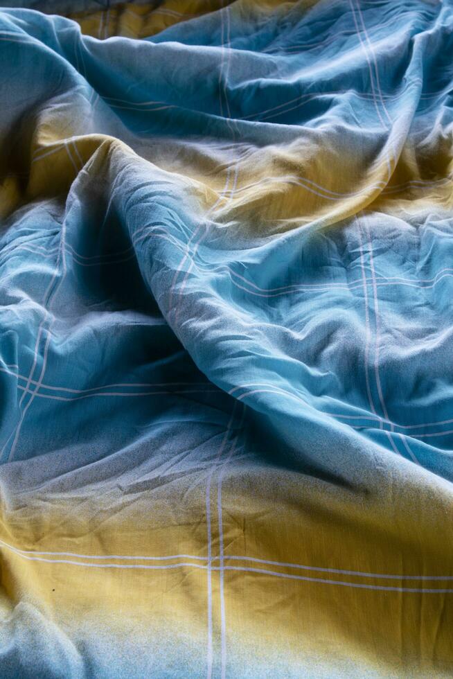 colorida cobertor dentro a desfeito cama e pastar luz foto